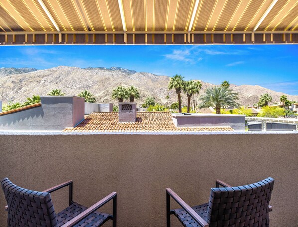 Une terrasse offrant une vue sur les montagnes, les palmiers et un ciel dégagé.