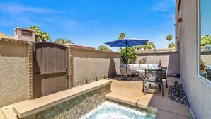 A backyard with a hot tub, patio furniture, and a covered seating area.