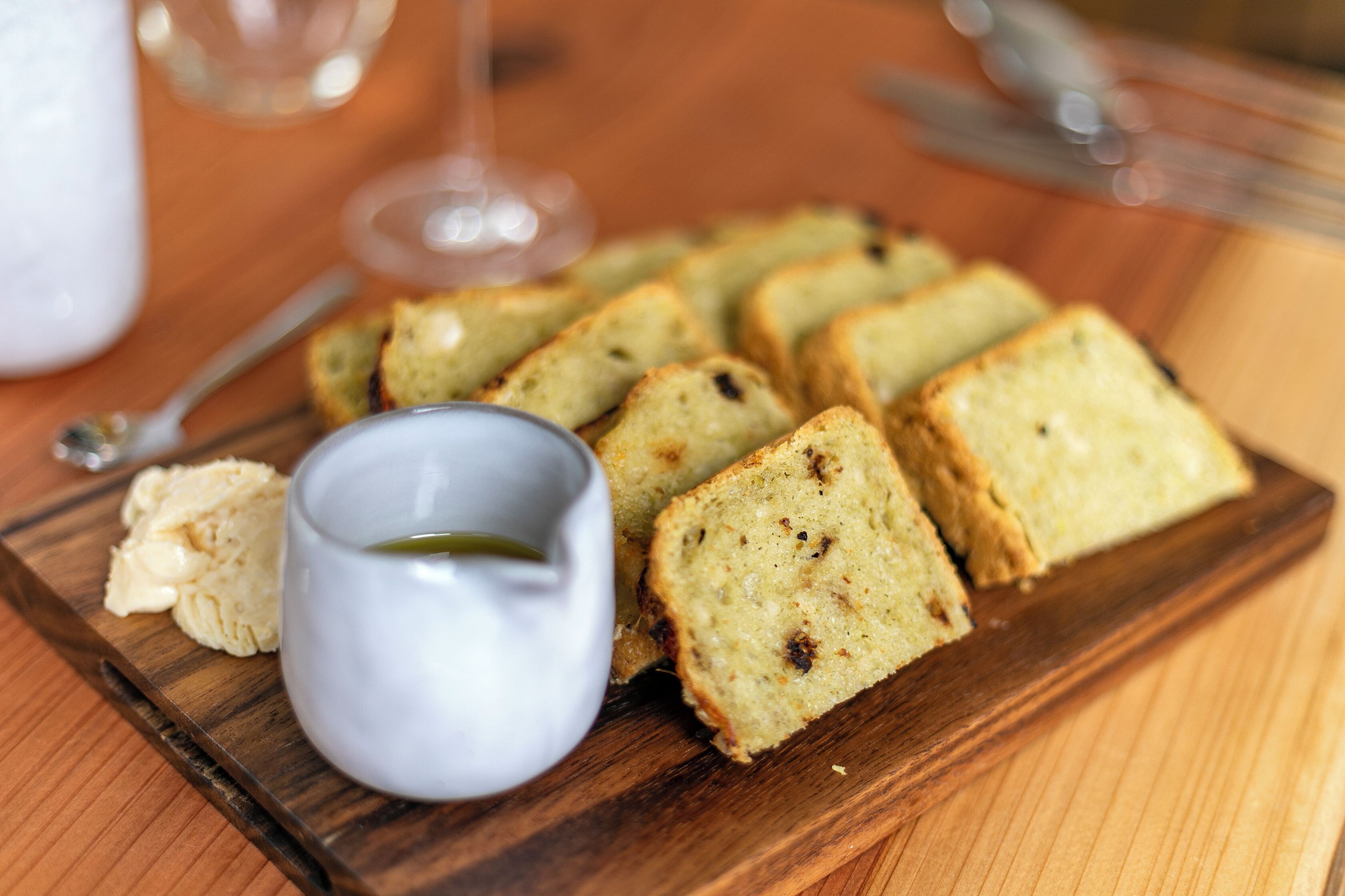 A wooden board with slices of cake and a small bowl of cream.