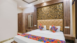 A bedroom with a large bed, a wooden wardrobe, and a decorative headboard. - FabHotel Shri Ram Kashi (Prayagraj)