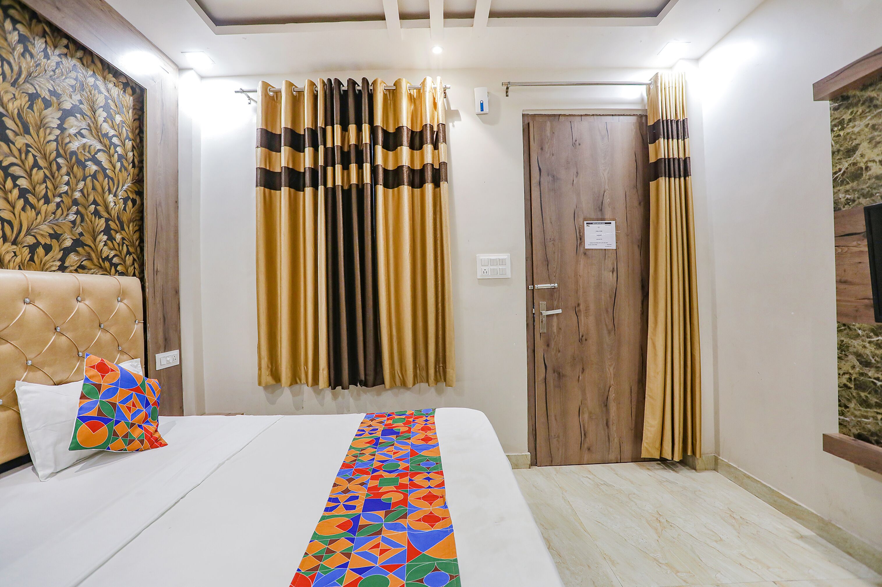 Una habitación de hotel con una cama, una puerta de madera y cortinas.