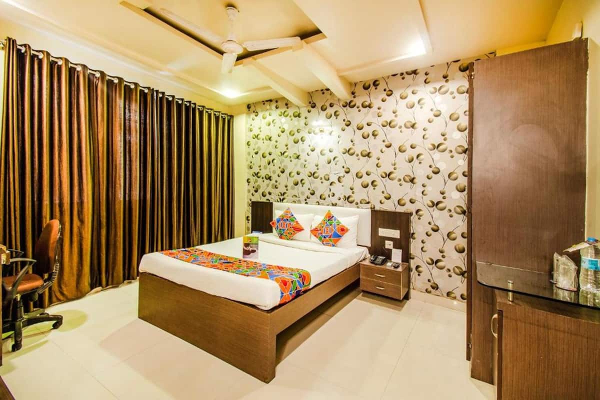 A hotel room with a bed, a desk, a chair, a wardrobe, and a bathroom.