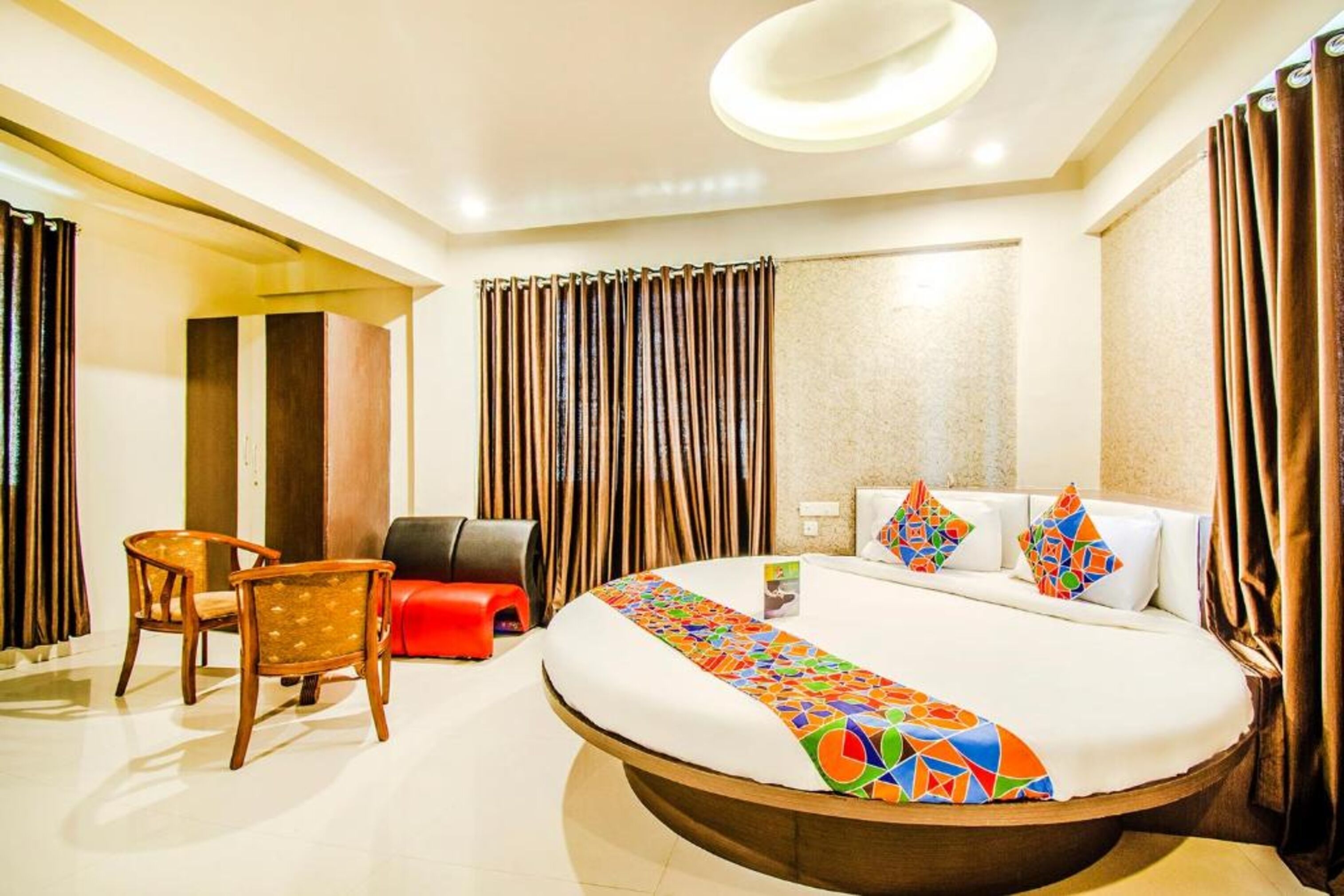 A hotel room with a large bed, a desk with a chair, and a small seating area.