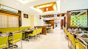 Un restaurant avec des banquettes et des tables, un luminaire au plafond et un décor mural à motifs.