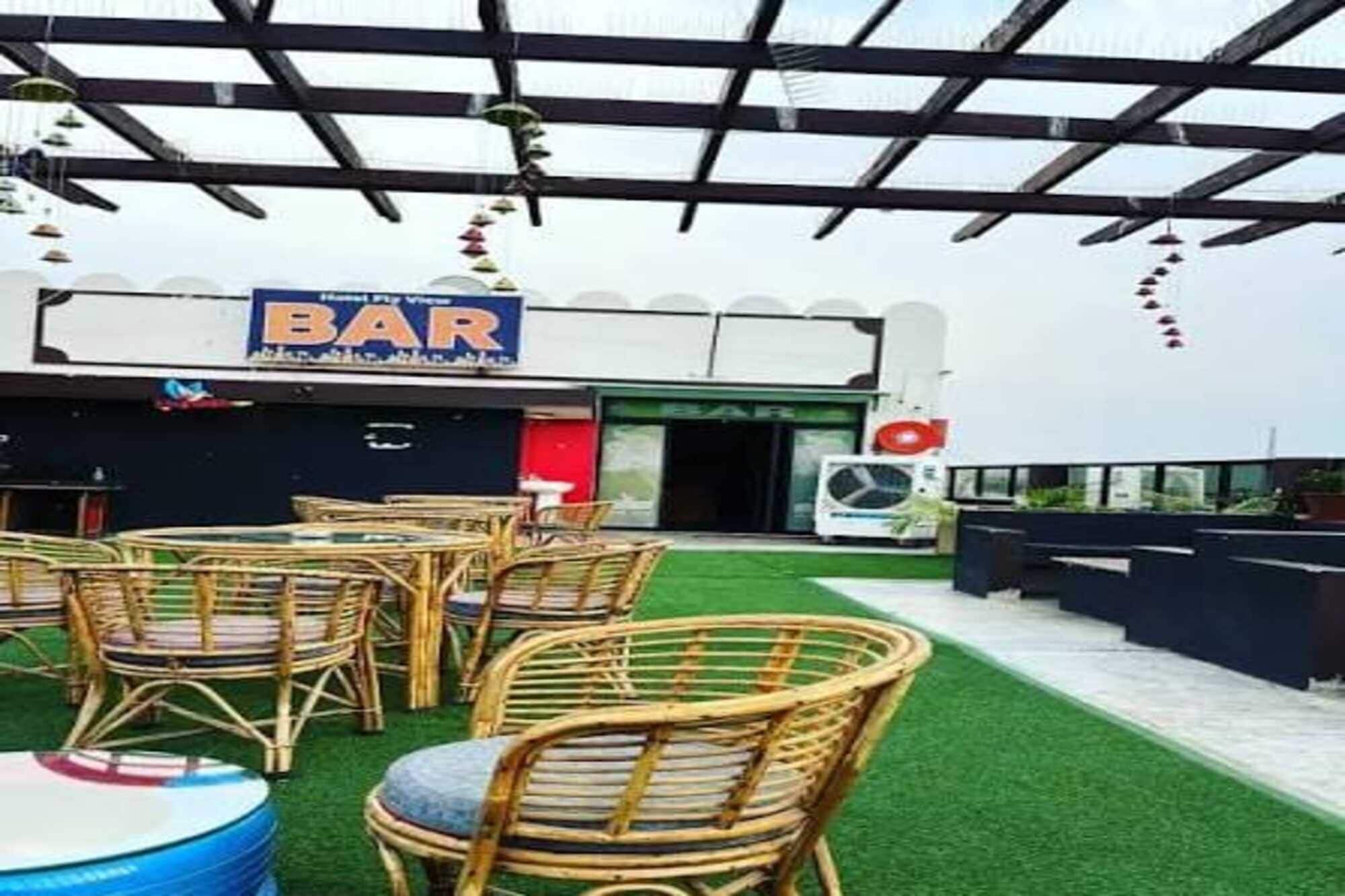 An outdoor seating area with wicker chairs and tables, a bar with a sign, and a green artificial turf.