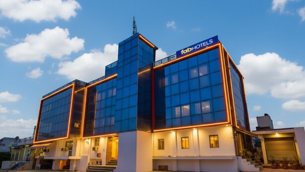 Un hotel moderno con fachada de vidrio, un cartel llamativo que dice "fabHOTELS" y una entrada bien iluminada.