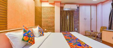 Una habitación de hotel con cama, armario, una mesita y una silla.