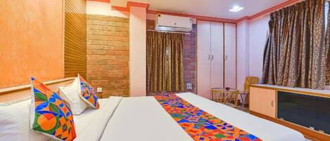 A hotel room with a bed, a TV, a small table, and a wardrobe.