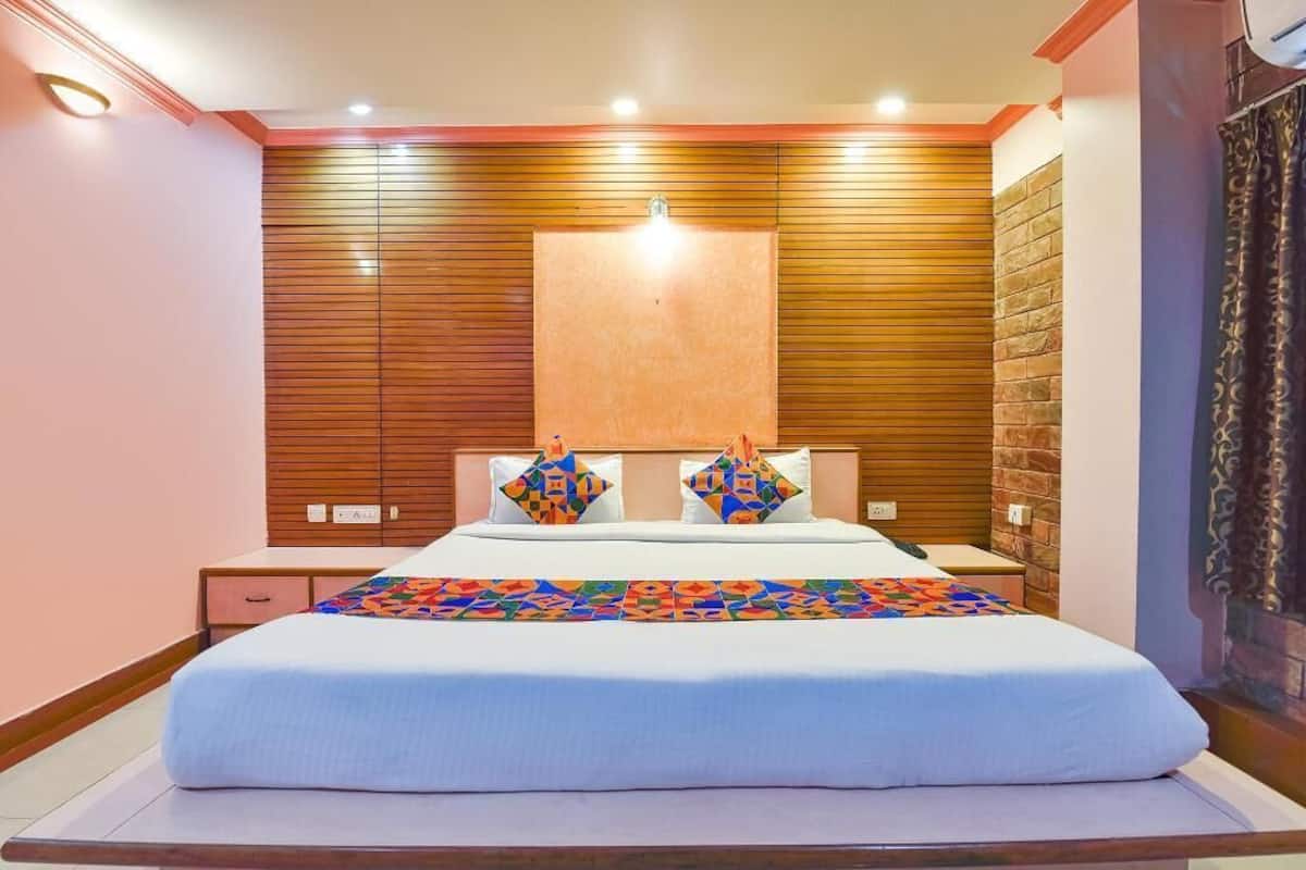 A bedroom with a large bed, wooden panel walls, a brick accent wall, and a decorative pillow.