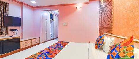 A bedroom with a bed, a TV, a wardrobe, and a door leading to another room.