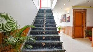 Una escalera de mármol con diseños geométricos, que conduce a una puerta con marco de madera.
