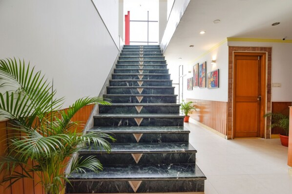 Un escalier en marbre orné de motifs géométriques, menant à une porte dotée d’un cadre en bois.