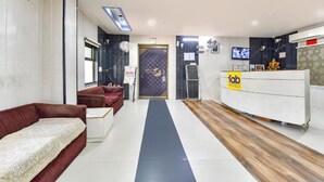 Zona de recepción de un hotel con un mostrador, un sofá y una mesa de recepción.