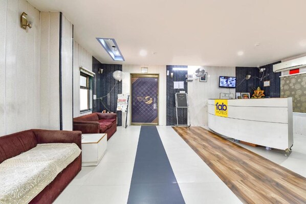 A hotel reception area with a reception desk, a sofa, and a reception counter. - FabHotel Fly view (Jaipur)