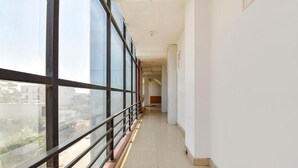 Un pasillo con ventanas amplias, suelo de baldosas y vistas al exterior.