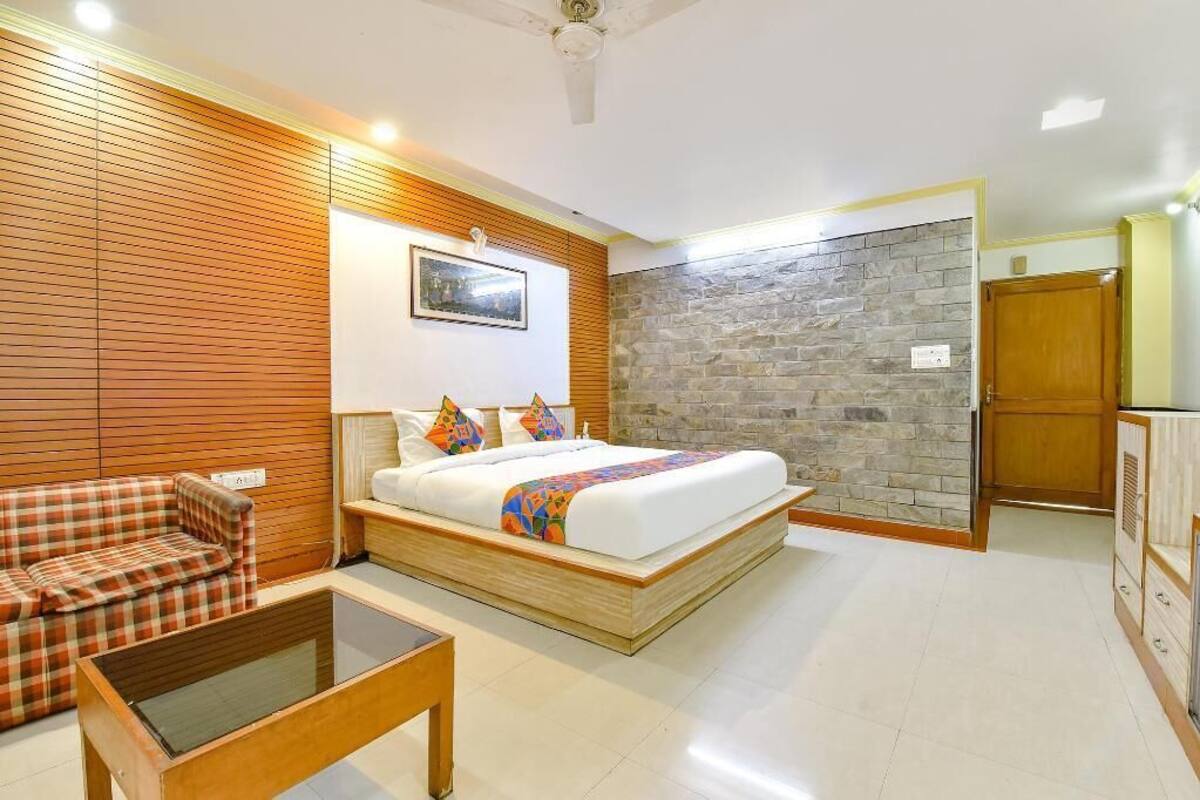 A bedroom with a bed, a sofa, a small table, a stone wall, and a wooden door.