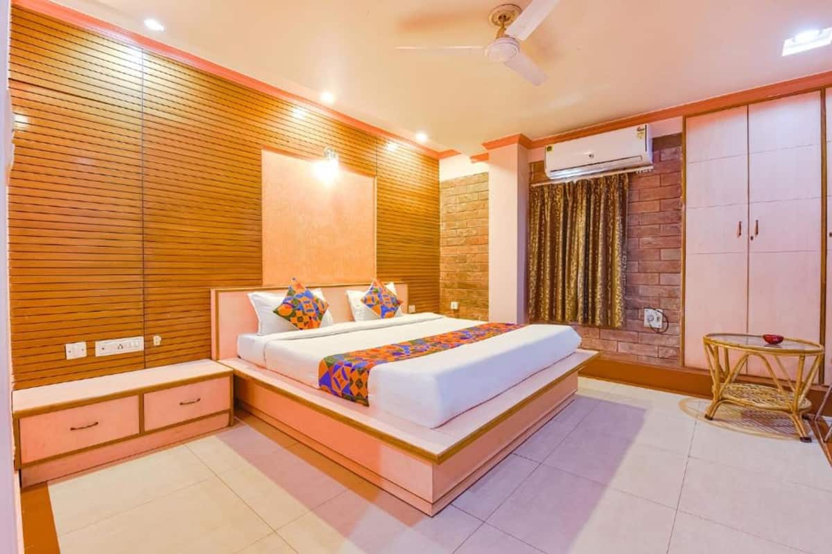 A modern bedroom with a wooden slat wall, a large bed with a colorful blanket, a small bedside table, and a wardrobe.