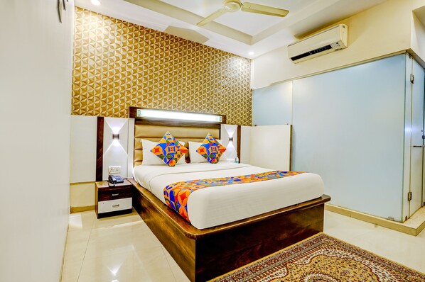 A modern bedroom with a wooden bed, patterned wallpaper, a nightstand, a bedside table, and a ceiling fan. - Fabhotel Kwality Inn (Mumbai)