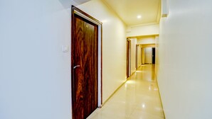 Un pasillo con puerta de madera, un interruptor de luz y suelo de baldosas.