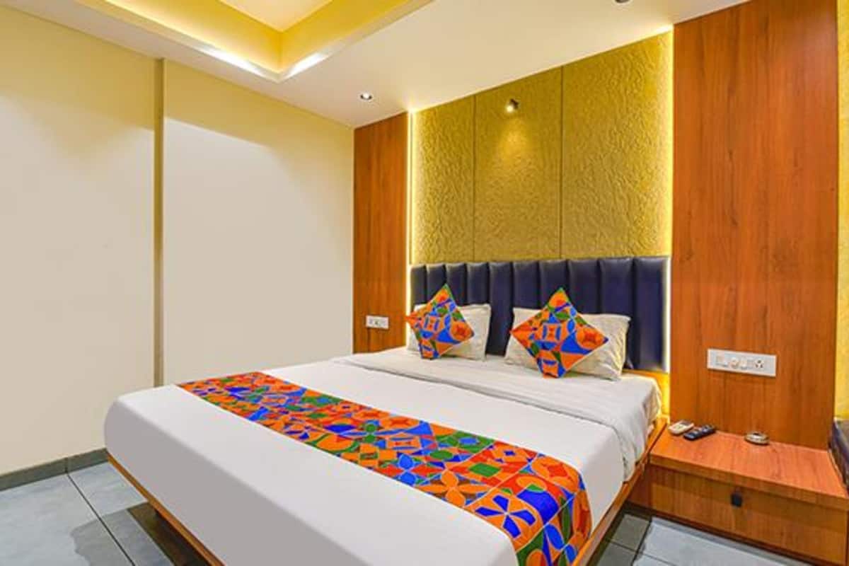 A hotel room with a large bed, a wooden headboard, and a nightstand with a phone.