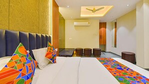 A hotel room with a large bed, a ceiling fan, and a view of the hallway. - Fabhotel Udhna Inn (Surat)