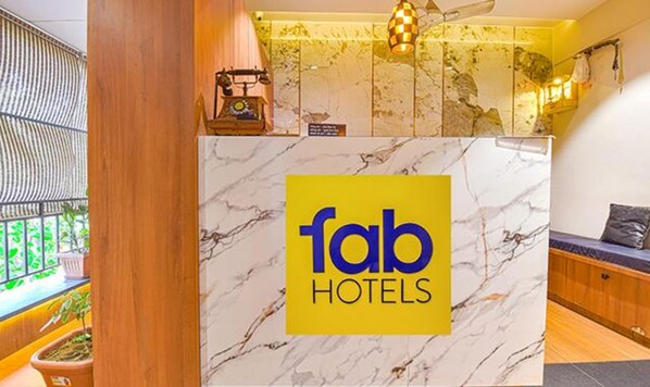 A reception desk with a marble top and a yellow sign reading "fab hotels".