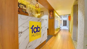 A reception area with a marble counter, a 'fab hotels' sign, wooden flooring, and a corridor with doors. - Fabhotel Udhna Inn (Surat)