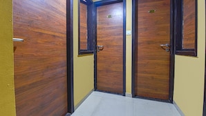 A hallway with wooden doors and a yellow wall. - Fabhotel Rb Residency (Surat)