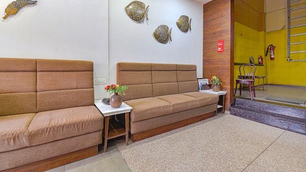 A reception area with a sofa, a small table with a vase, and wall art. - Fabhotel Rb Residency (Surat)
