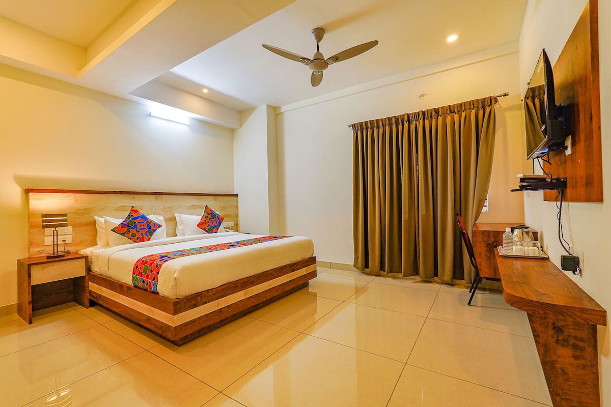 A hotel room with a bed, a nightstand, a desk, a television, and a ceiling fan.