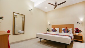 A bedroom with a bed, a desk, a chair, a ceiling fan, and a mirror. - FabHotel GK Residency (New Delhi)