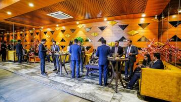 A modern hotel lobby with geometric wall patterns, round tables, and yellow seating areas.