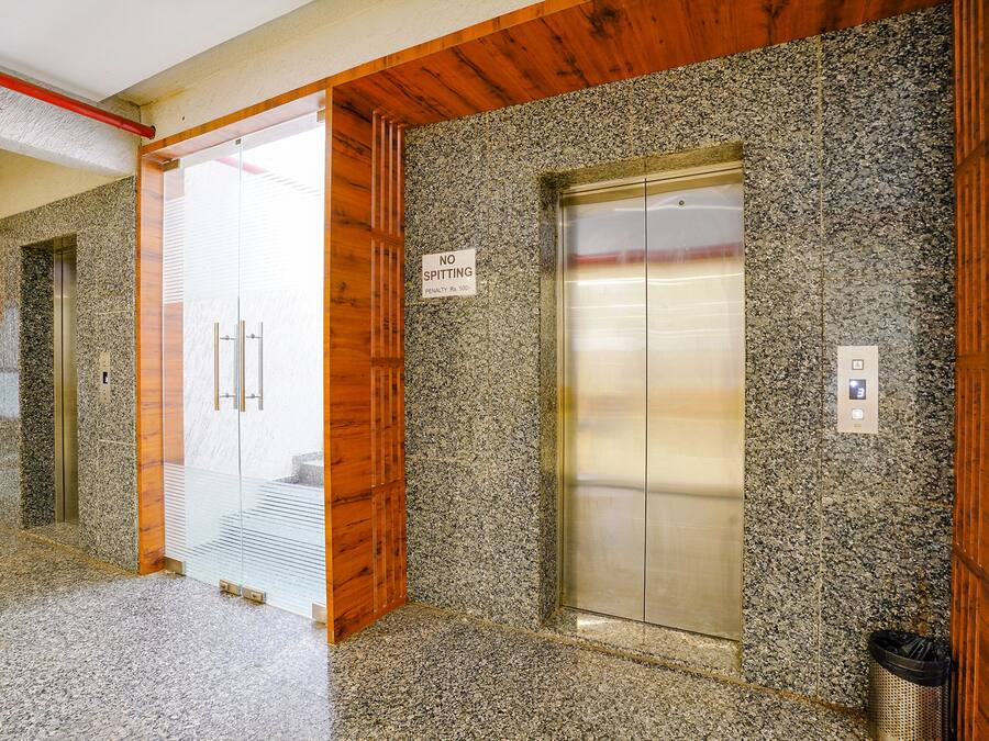 Un ascensor con pared de granito y un cartel que indica que está prohibido escupir.