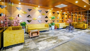 A lobby with yellow sofas, a wooden ceiling, and geometric wall patterns. - Fabhotel La Victoria (Surat)