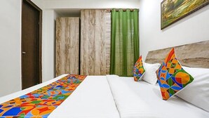 A hotel room with a bed, a wooden wardrobe, and a green curtain. - Fabexpress Premium Room I (New Delhi)