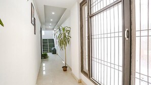 A corridor with a potted plant, a metal gate, and a staircase in the background. - Fabexpress Premium Room I (New Delhi)