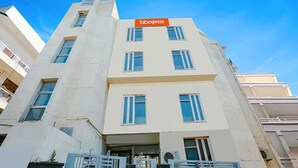 A modern building with a flat facade, multiple windows, and a visible entrance. - Fabexpress Premium Room I (New Delhi)