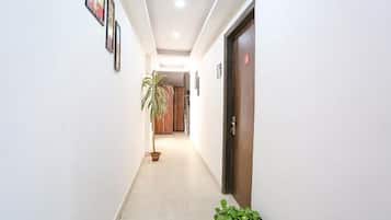 A hallway with a potted plant, a door, and framed pictures on the wall.