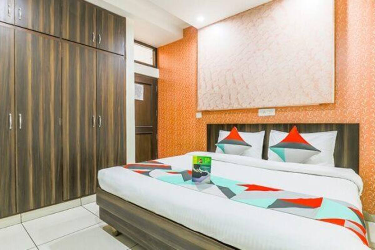 A hotel room with a bed, a wardrobe, and a patterned wall.