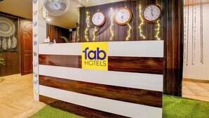 Un comptoir d’accueil avec une enseigne indiquant « fab hotels », plusieurs horloges et un ventilateur.