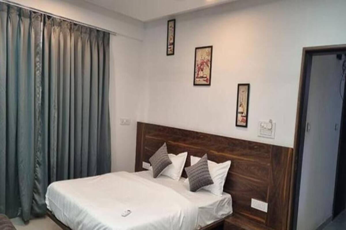 Ein Schlafzimmer mit Bett, Vorhängen, einem Holzkopfende und Wandbildern.