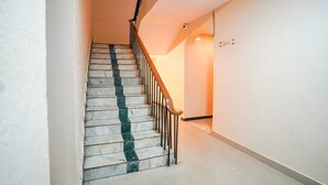 Una scala con gradini in marmo e ringhiere in legno, che conduce a un pianerottolo con un lampadario.