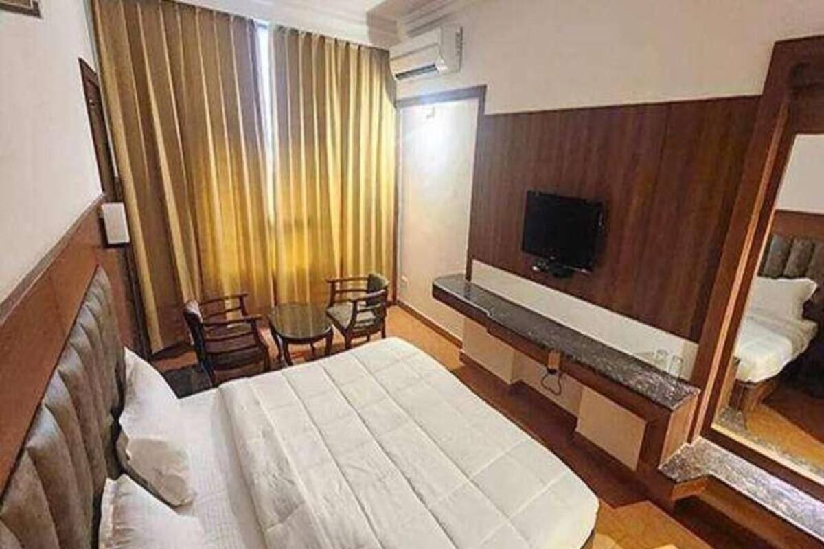 A hotel room with a bed, a desk, a chair, a television, and a mirror.
