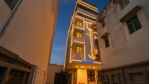 Un edificio moderno con un llamativo letrero de 'fab hotels', que presenta una fachada geométrica y una entrada central con escalones.