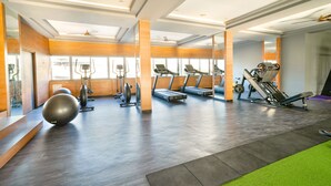Un gimnasio con cintas de correr, elípticas y pelotas de ejercicio.