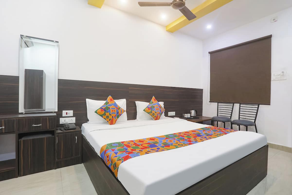 A hotel room with a bed, bedside table, nightstand, and a mirror.