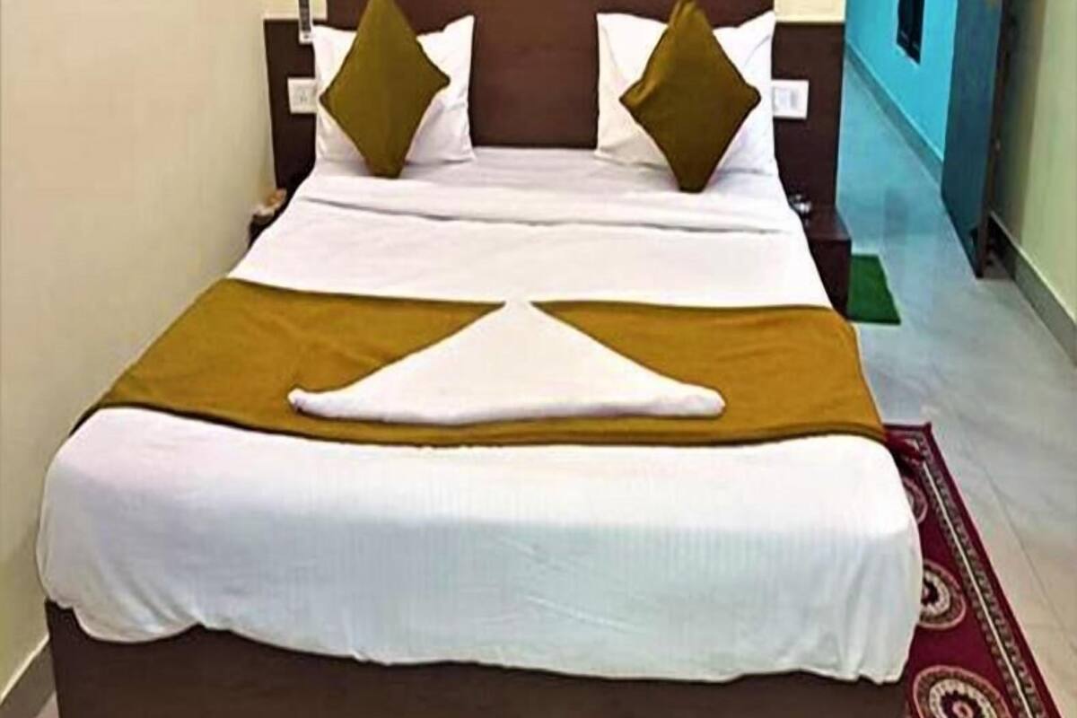 A neatly made bed with a brown headboard, white bedding, and two green pillows.