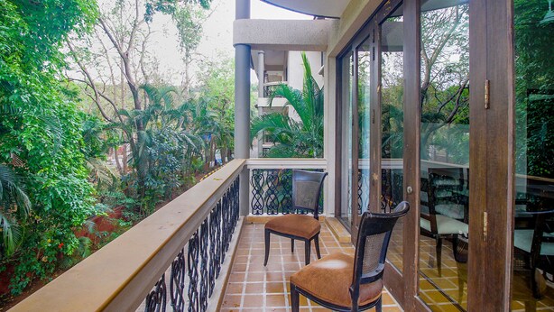 Un balcon donnant sur une végétation luxuriante, avec une chaise et une table.