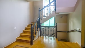 Un escalier en bois, agrémenté de rampes noires décoratives et d’un luminaire fixé au mur.