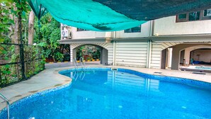 Une piscine dont le bord est revêtu de carrelage, entourée d’une clôture et de verdure.